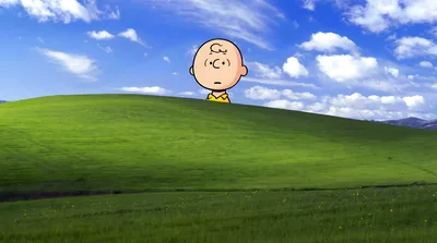 Charlie Brown peering over a classic green hill and blue sky for PC Wallpaper